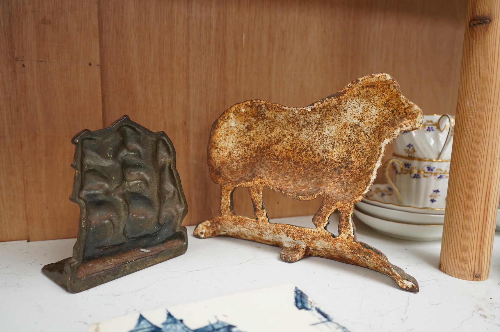 A Minton blue and white tile and two cast iron door stops, one in the form of a sheep, 24cm wide